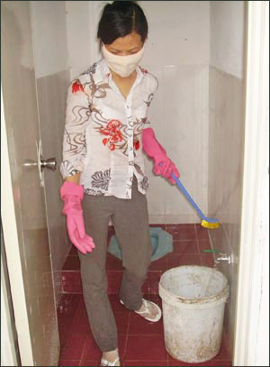 Bà Nguyễn Thị Hồng Oanh phải làm công việc dọn dẹp vệ sinh theo quyết định trái luật của nhà trường. Ảnh: NLĐ