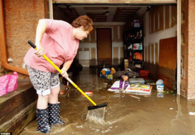 Chị Mona Goodman, Phó Chủ tịch Hội đồng TP Long Beach, lau dọn nhà cửa sau khi cơn bão Irene đi qua. Ảnh: GETTY IMAGES